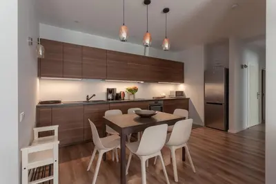 a kitchen with a wooden table and white chairs at Brand new flat heart of Vilnius in Vilnius
