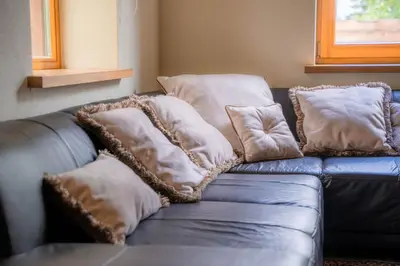 a blue leather couch with pillows on it at Remigija Studio Home in Jonava