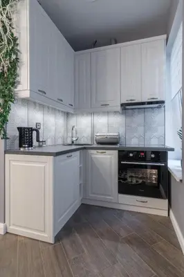a white kitchen with white cabinets and an oven at Dandelion apartment in the heart of Kaunas in Kaunas