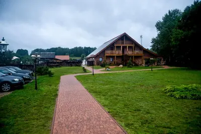 a large wooden house with cars parked in front of it at Dzūkijos dvaro 