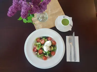 a white plate of food with vegetables on a table at Dzūkijos dvaro 