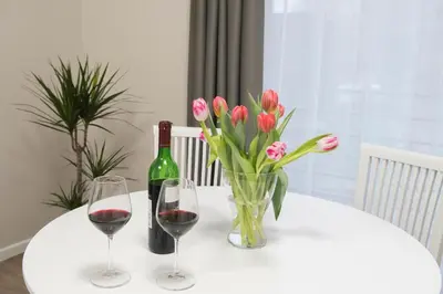 a table with two glasses of wine and a vase of flowers at Green Hill Apartments in Kaunas