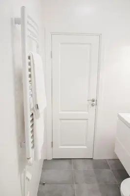 a white bathroom with a white door and a sink at Green Hill Apartments in Kaunas