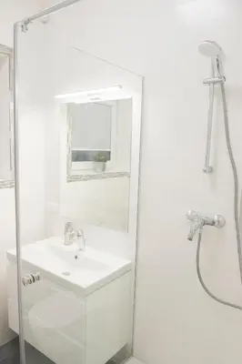 a white bathroom with a sink and a shower at Green Hill Apartments in Kaunas