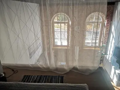 two windows with curtains in a room with a couch at Botanical Garden Studio in Kaunas