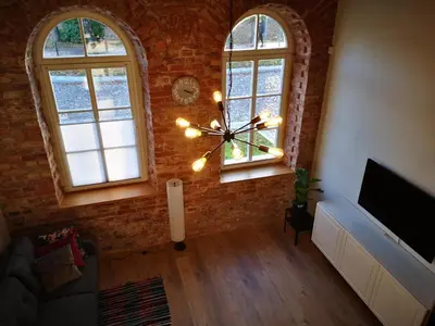 a living room with a brick wall and a large clock at Botanical Garden Studio in Kaunas