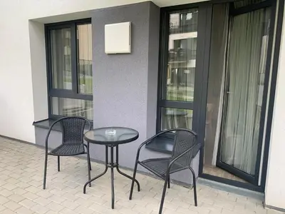 a patio with two chairs and a table and some windows at Near Ozas Studio in Vilnius
