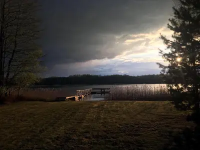 a dock on a lake with the sun shining at Baublys Lake Lodge in Viktarinas