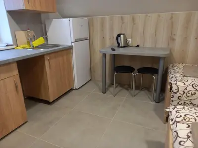 a kitchen with a refrigerator and a table and two stools at ROOMS FOR RENT in Panevėžys