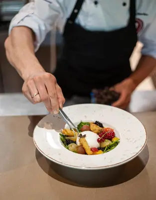 a person cutting a plate of food with a fork and knife at Ego SPA - Adults Only in Birštonas