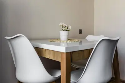 two white chairs around a table with a vase of flowers at Scandinavian inspired design in Vilnius