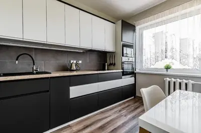 a kitchen with black and white cabinets and a table at Scandinavian inspired design in Vilnius