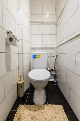 a bathroom with a toilet in a white tiled room at Scandinavian inspired design in Vilnius