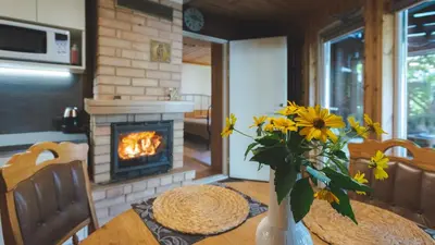 a table with a vase of flowers and a fireplace at Namelis prie Magnolijos in Druskininkai