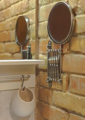 a bathroom with two mirrors on a brick wall at Namelis prie Magnolijos in Druskininkai