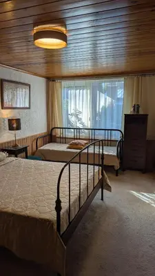 a bedroom with two beds and a large window at Namelis prie Magnolijos in Druskininkai