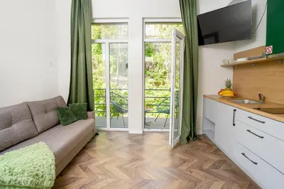 a living room with a couch and a kitchen with sliding glass doors at House 22A Studio Apartments in Kaunas