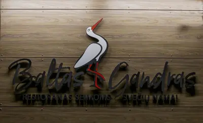 a sign with a white bird on a wooden floor at Baltas gandras in Naisiai