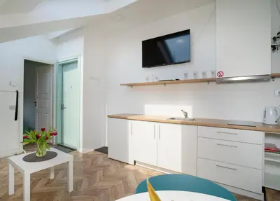 a kitchen with white cabinets and a tv on the wall at House 22A Apartments in Kaunas