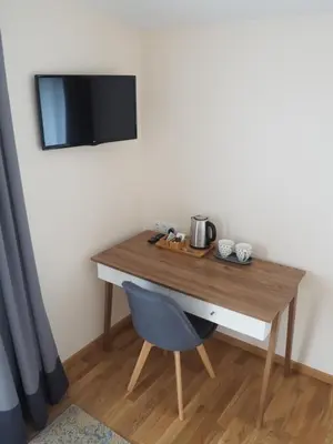 a wooden desk with a chair and a tv on a wall at Svečių namai Žara in Tytuvėnai