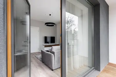 a living room with a sliding glass door with a television at #stayhere - Central Castle View Riverside Apartment in Vilnius