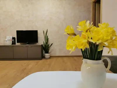 a vase filled with yellow flowers sitting on a table at Central Apartments Nojus in Druskininkai