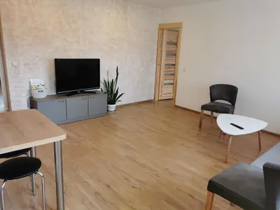 a living room with a flat screen tv and chairs at Central Apartments Nojus in Druskininkai