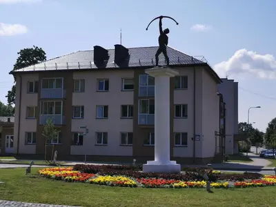 a statue of a man on a column in front of a building at Central Apartments Nojus in Druskininkai