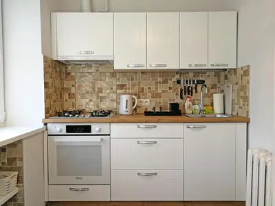 a kitchen with white cabinets and a stove top oven at Šiauliai Central Apartment @ Trakų street in Šiauliai