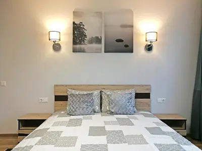 a bedroom with a bed with two lights on the wall at Šiauliai Central Apartment @ Trakų street in Šiauliai