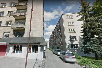 a car driving down a street next to buildings at Šiauliai Central Apartment @ Trakų street in Šiauliai
