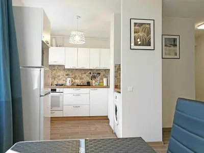 a kitchen with white cabinets and a blue chair at Šiauliai Central Apartment @ Trakų street in Šiauliai
