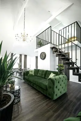 a living room with a green couch and a staircase at Luxury Loft in Kaunas