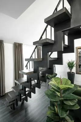 a black spiral staircase in a living room with a plant at Luxury Loft in Kaunas