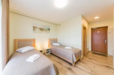 a bedroom with two beds and a hallway with a door at Motel Panorama in Šiauliai
