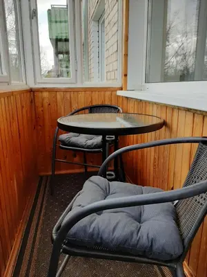 a table and chairs in a room with two windows at Trumpalaikė nuoma centre in Šiauliai