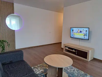 a living room with a tv and a chair and a table at Trumpalaikė nuoma centre in Šiauliai