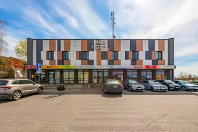 a building with cars parked in a parking lot at Air Kaunas in Karmėlava