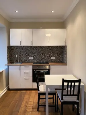 a kitchen with white cabinets and a table and chairs at Studio flat in Kedainiai in Kėdainiai