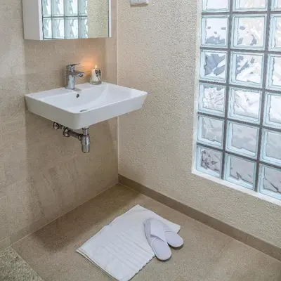 a bathroom with a sink and a towel on the floor at Sodyba Pelėdų medus in Vainekoniai