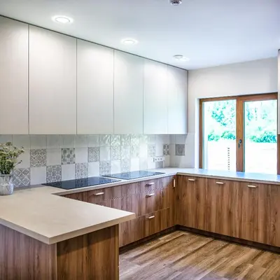 a kitchen with wooden cabinets and a window at Sodyba Pelėdų medus in Vainekoniai