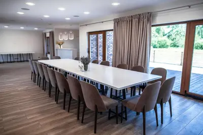 a dining room with a large white table and chairs at Sodyba Pelėdų medus in Vainekoniai
