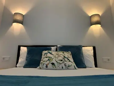 a bedroom with a bed with blue pillows and two lights at COZY Nest apartment in Kaunas in Kaunas
