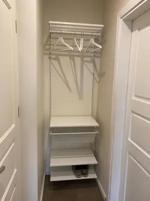 a walk in closet with white shelves and a door at 