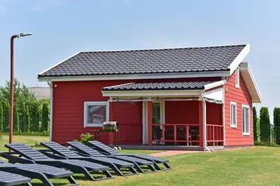 a red house with chairs in front of it at Villa Ievyne 2 in Paežeriai