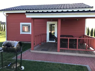 a red house with a deck with a grill at Villa Ievyne 2 in Paežeriai