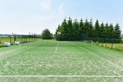 a tennis court with a net and some trees at Villa Ievyne 2 in Paežeriai
