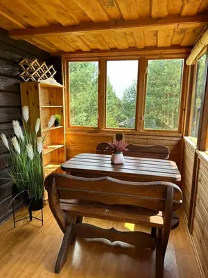 a wooden dining room with a table and a bench at Sodyba Vilagio in Alanta