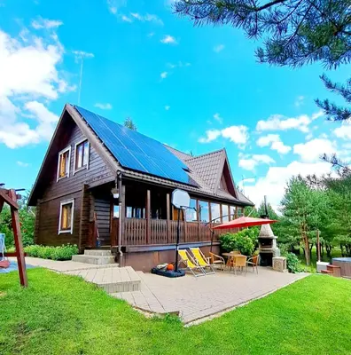 a house with a solar roof and a patio at Sodyba Vilagio in Alanta