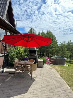 a table and chairs under a red umbrella on a patio at Sodyba Vilagio in Alanta
